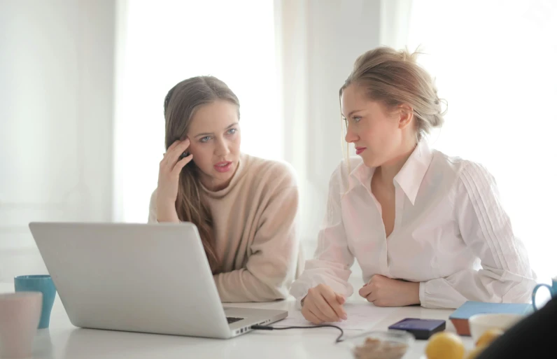 two women sitting at a table looking at a laptop, a cartoon, pexels, looking confused, professional photo, wearing a white blouse, background image