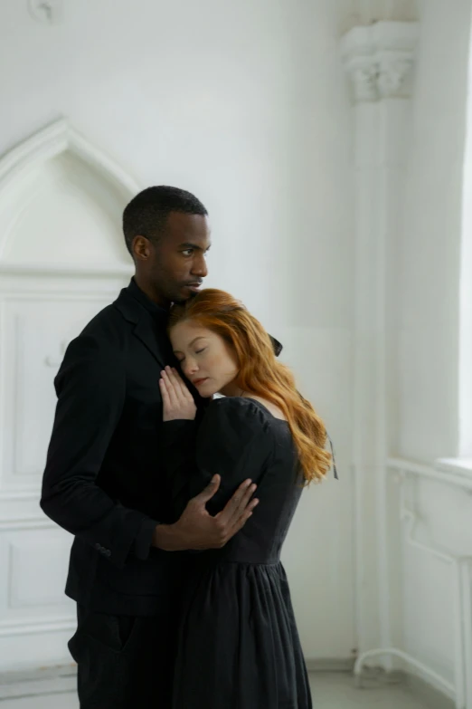 a man standing next to a woman in a black dress, inspired by Gordon Parks, international gothic, eleanor tomlinson, in a white room, holding each other, funeral