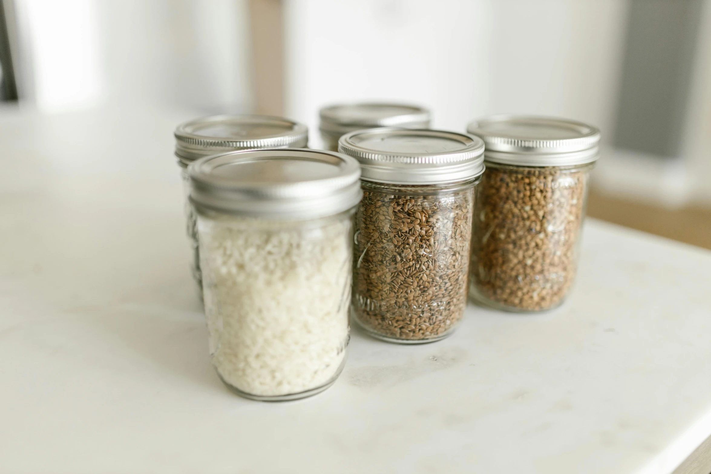 a group of jars filled with rice sitting on top of a counter, gravel, detailed product image, petite, mason