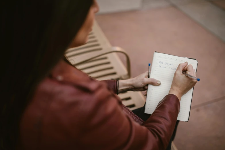 a woman sitting on a bench writing in a notebook, by Emma Andijewska, pexels contest winner, top-down shot, 15081959 21121991 01012000 4k, over the shoulder shot, performing