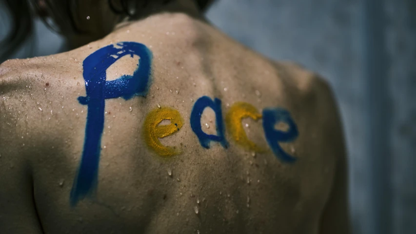 a woman with the word peace painted on her back, trending on pexels, prussian blue and azo yellow, avatar image, wet on wet, artem chebokha