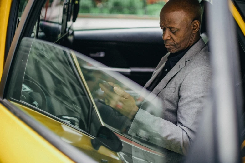 a man sitting in the driver's seat of a taxi, happening, lance reddick, looking at his phone, profile image, maintenance