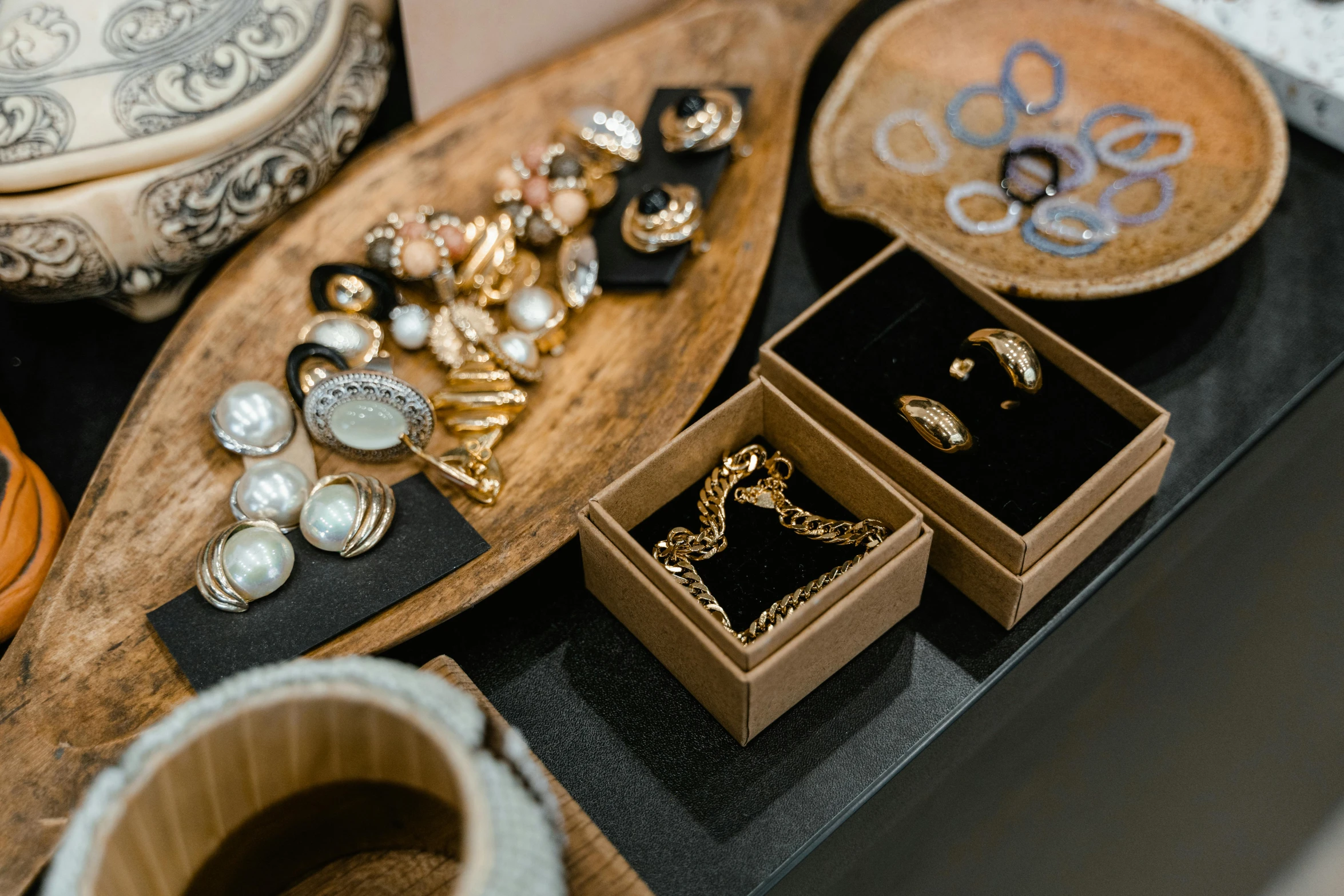 a pile of jewelry sitting on top of a table, trending on pexels, gold and black color scheme, on a wooden tray, manuka, presenting wares