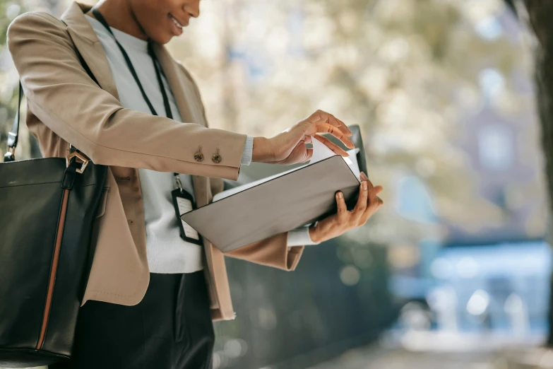 a close up of a person holding a laptop, an album cover, by Carey Morris, pexels contest winner, private press, woman in business suit, delivering mail, read a directory book, sustainable materials