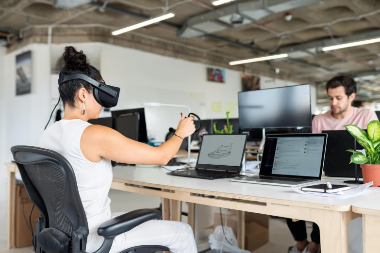 a woman sitting at a desk using a virtual reality headset, a computer rendering, by Nicolette Macnamara, unsplash, in a open-space working space, avatar image, 9 9 designs, using a exoskeleton