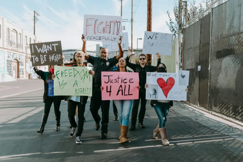 a group of people walking down a street holding signs, a photo, by Julia Pishtar, pexels, 1600 south azusa avenue, justice, avatar image, fight