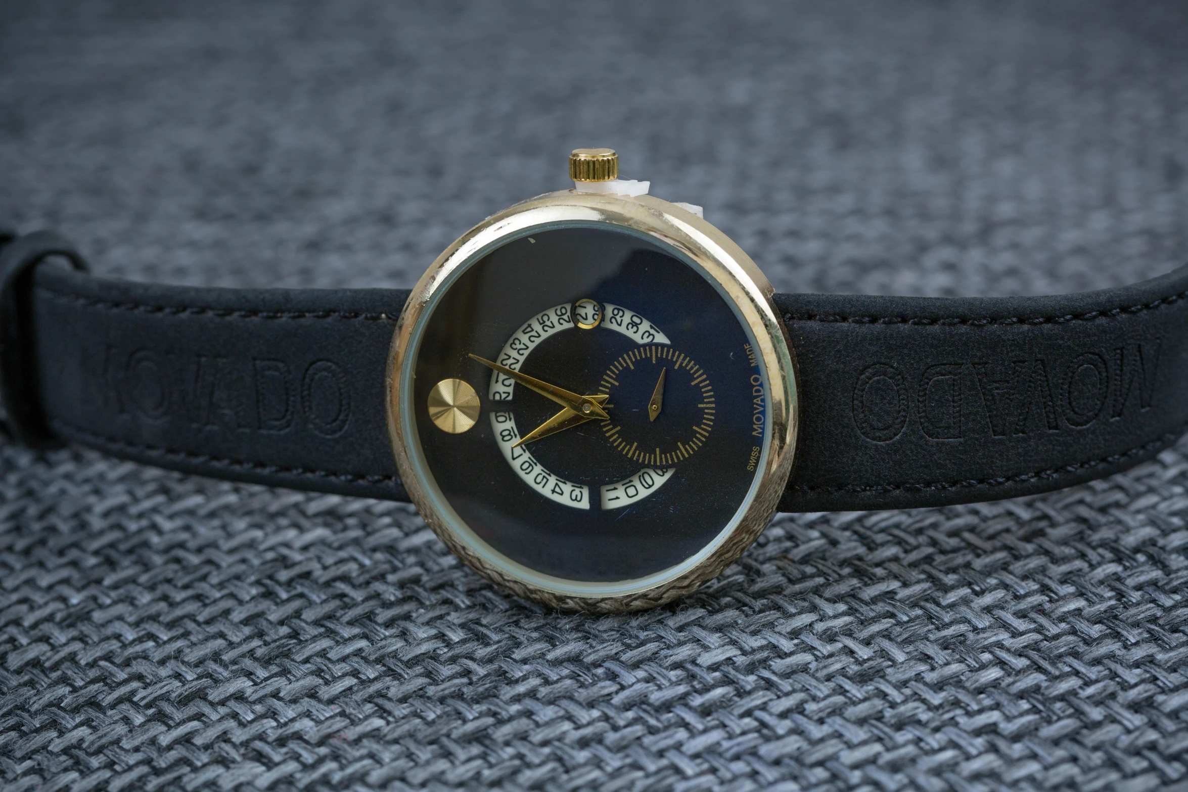 a close up of a wrist watch on a table, neo-dada, gold and black blu, high detailed photo, bizzaro, enso