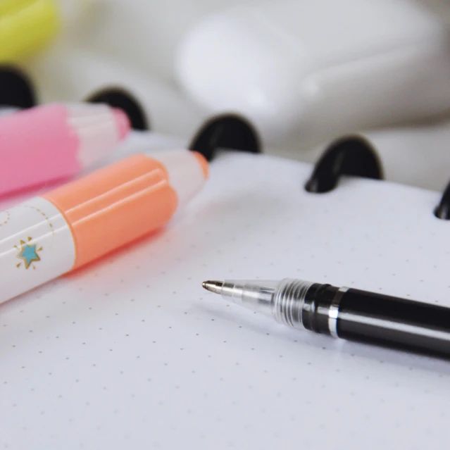 a bunch of pens sitting on top of a notebook, by Julia Pishtar, trending on pexels, white neon details, polka dot, close-up product photo, medibang