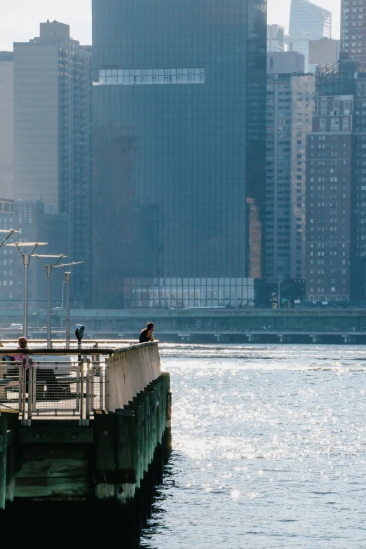 a group of people standing on top of a pier next to a body of water, a picture, by John Haberle, trending on unsplash, hudson river school, a still of kowloon, late afternoon light, slide show, where a large