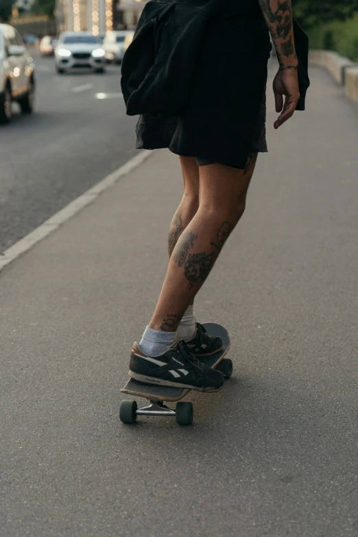 a man riding a skateboard down a street, a tattoo, trending on unsplash, gray shorts and black socks, androgynous person, taken in the late 2010s, instagram story