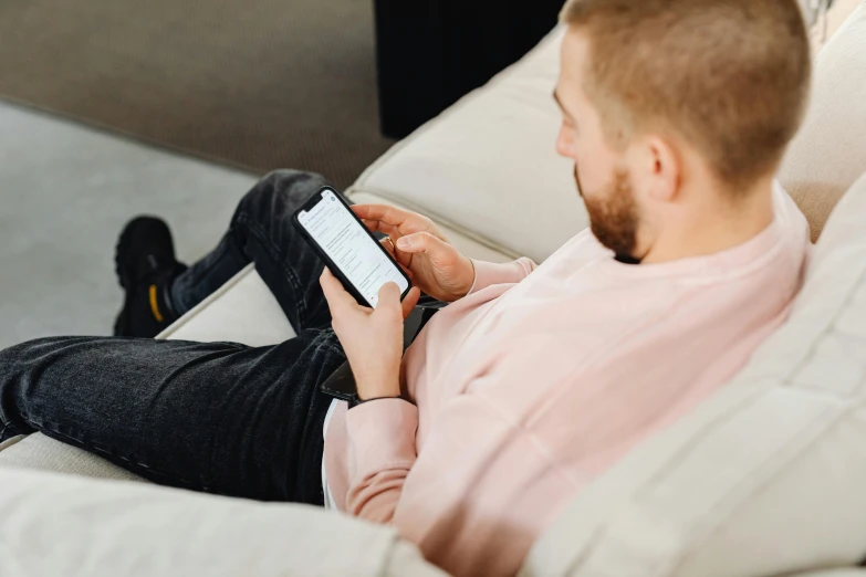 a man sitting on a couch using a cell phone, trending on pexels, rectangle, laying down, casual game, 1 2 9 7