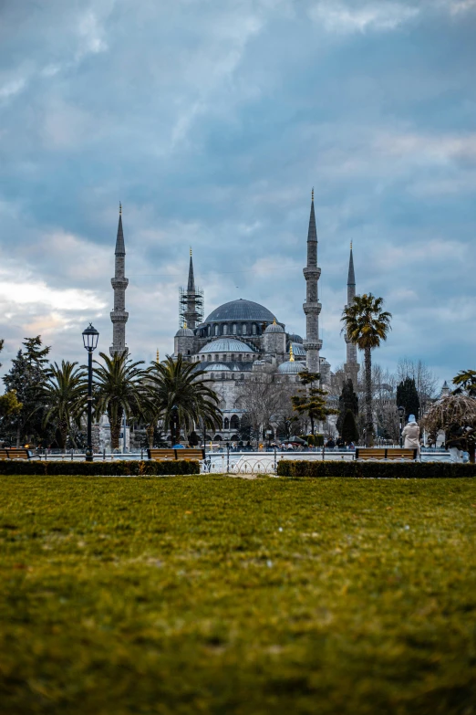 a large building sitting on top of a lush green field, a colorized photo, inspired by Altoon Sultan, pexels contest winner, hurufiyya, cathedral in the background, 🚿🗝📝, square, grey and blue theme