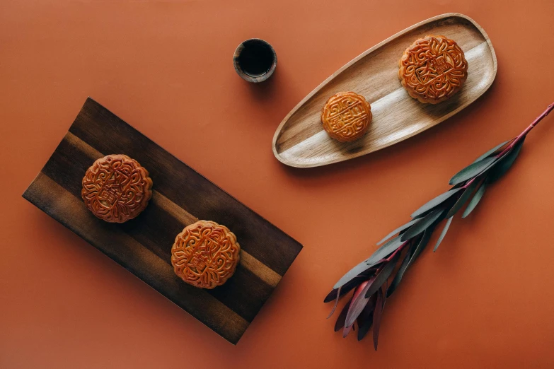 a close up of a plate of food on a table, a still life, inspired by Gu An, trending on unsplash, hurufiyya, crispy buns, intricate carved wood, orange color theme, thumbnail