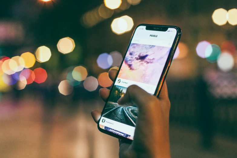 a person taking a picture of a street at night, trending on pexels, ios app icon, phone background, casually dressed, bokeh. i