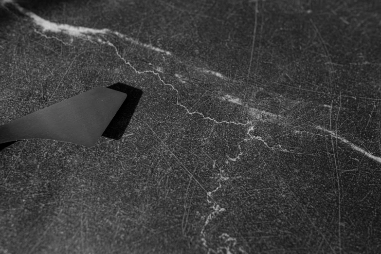 a black and white photo of a knife on a table, an ultrafine detailed painting, by Daniel Gelon, concrete art, cracks of magma, dutch angle from space view, glowing cracks, ultrafine detail