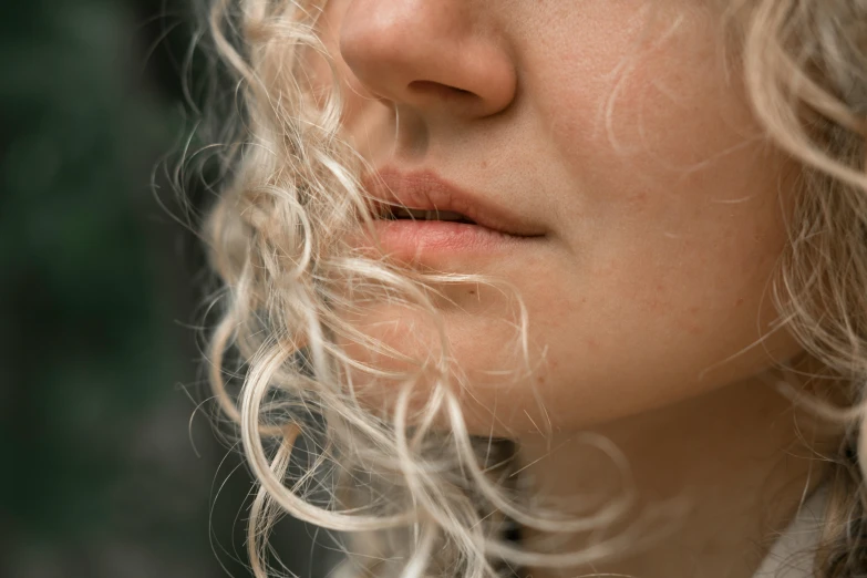 a close up of a woman with curly hair, a stipple, trending on pexels, soft chin, curly blond, lip scar, hair flowing down