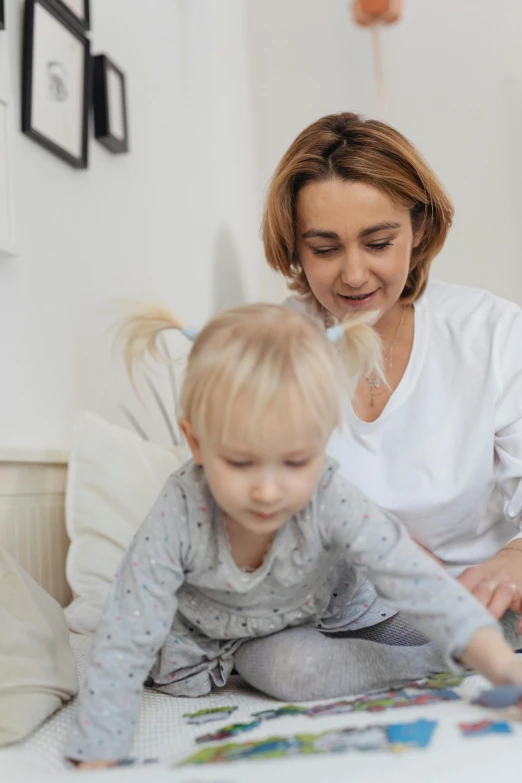 a woman sitting on top of a bed next to a child, on a white table, connectivity, zoomed in, thumbnail