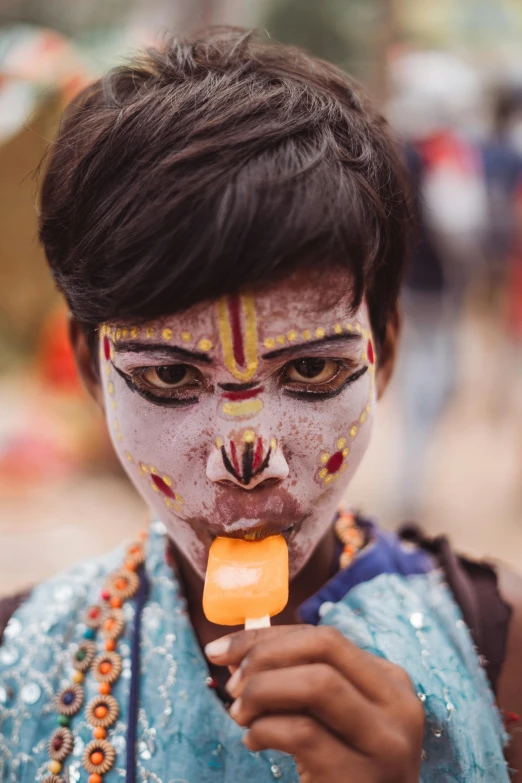 a close up of a person eating a popsicle, bengal school of art, tribal facepaint, orange, square, market