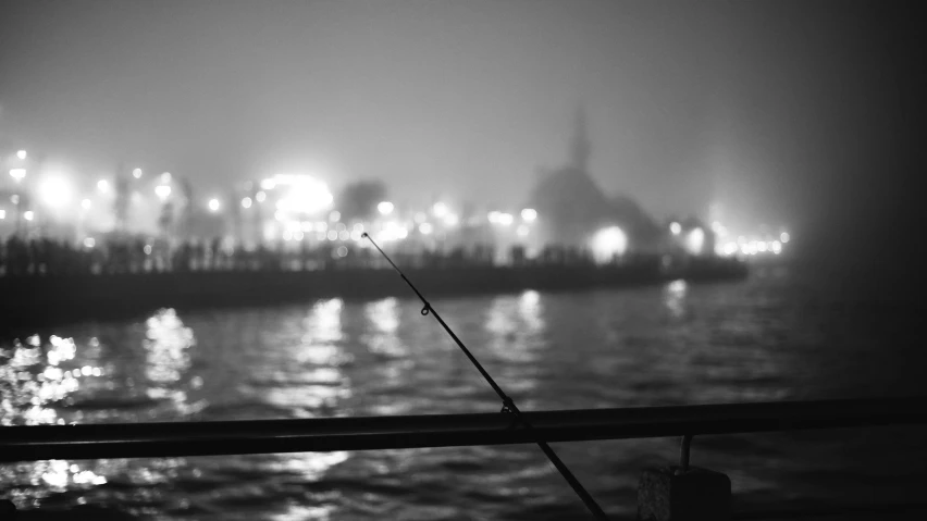 a black and white photo of a fishing rod, a black and white photo, by Gusztáv Kelety, pexels, tonalism, city midnight mist lights, hasselblad film bokeh, fish, night sea