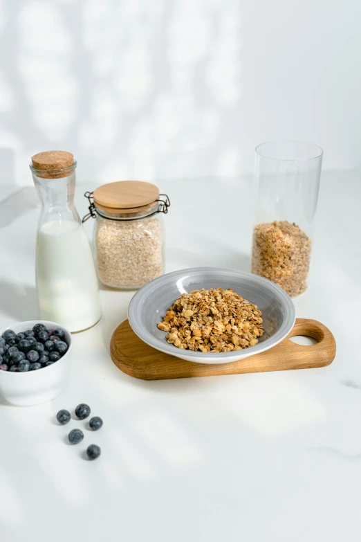 a table topped with a bowl of cereal next to a bottle of milk, a still life, pexels, blueberries on the side, sustainable materials, detailed product image, grey