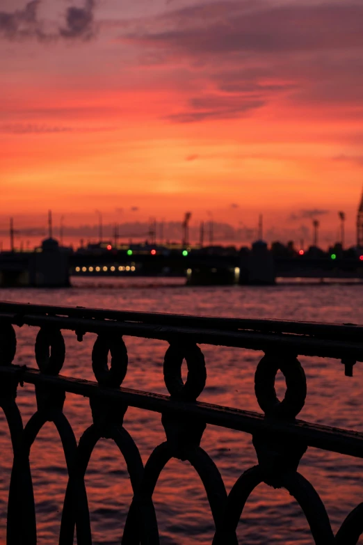 the sun is setting over a body of water, a picture, inspired by Nadim Karam, happening, bridges and railings, soft red lights, trending photo, saint petersburg