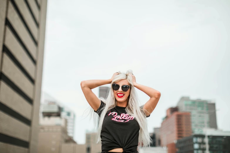 a woman standing in the middle of a city, trending on pexels, graffiti, long silver hair, wearing a marijuana t - shirt, cheeky smile with red lips, outlive streetwear collection