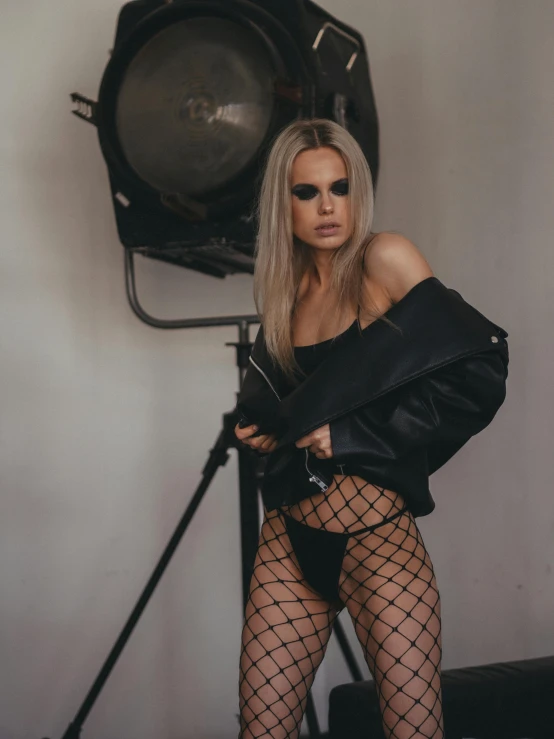 a woman in fishnets posing in front of a camera, inspired by Hedi Xandt, trending on pexels, cara delevigne, behind the scenes photo, wearing leather, caroline gariba