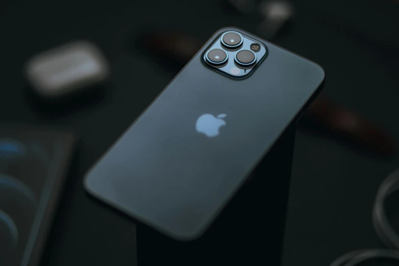 an apple iphone sitting on top of a table, by Adam Marczyński, trending on pexels, photorealism, iphone 12 camera, dark black porcelain skin, 256x256, towering over the camera