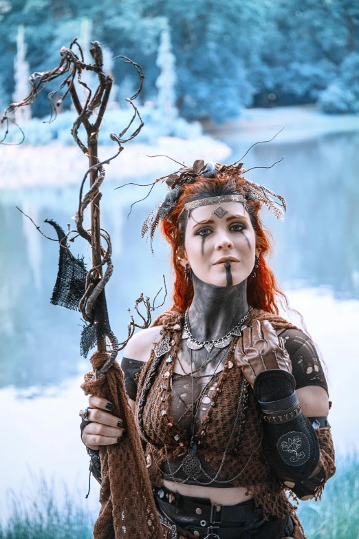 a woman with red hair holding a stick, a character portrait, by Kristian Zahrtmann, pexels contest winner, dressed as a scavenger, tree druid, ice queen, tribal clothing