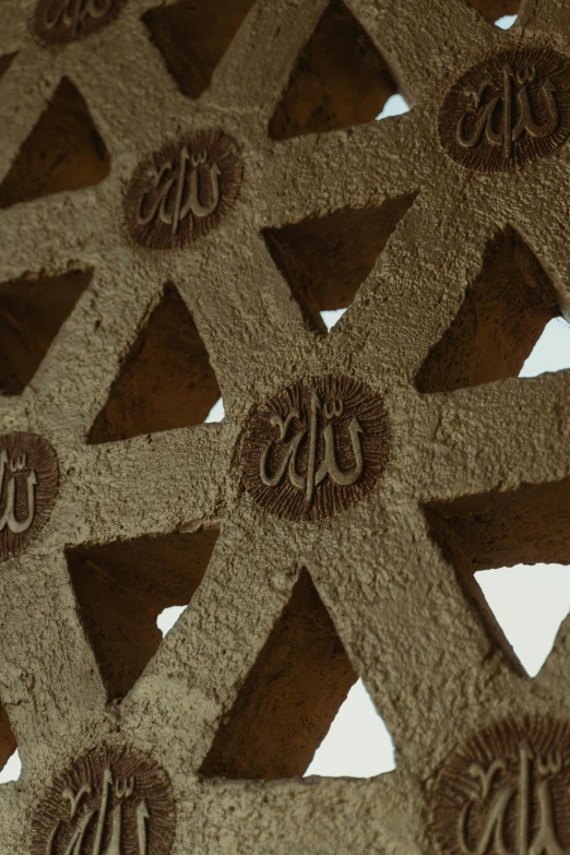 a close up of a decorative object with arabic writing on it, inspired by Ai Weiwei, unsplash, concrete art, vaulted ceiling, lattice, brown, insibidi symbols