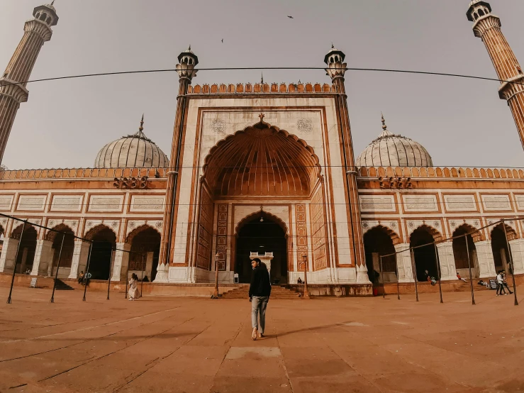 a person standing in front of a large building, pexels contest winner, arabesque, india, islamic, background image, walking towards the camera