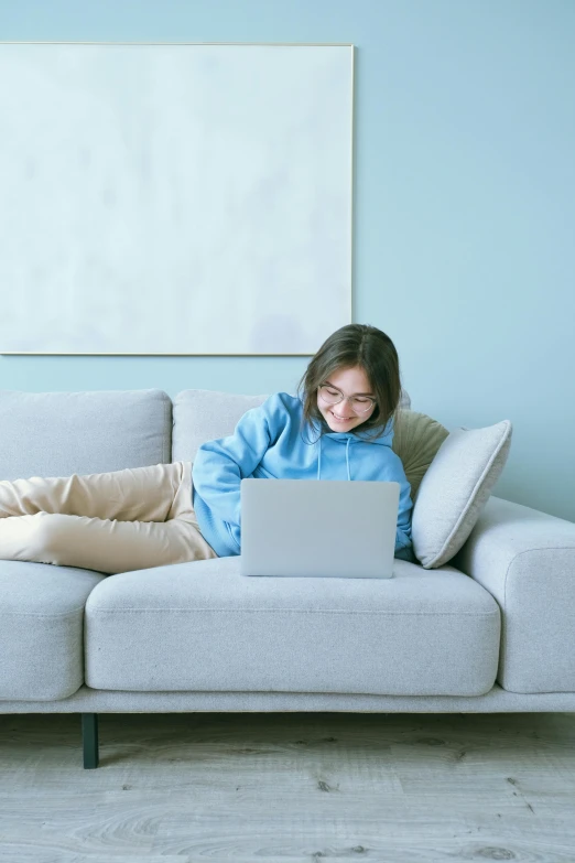 a woman sitting on a couch using a laptop, pastel blue, trending in japan, li zixin, very comfy]