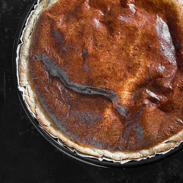 a close up of a pie in a pan on a table, by Daniel Gelon, baked bean skin texture, detailed product image, hegre, back - lit