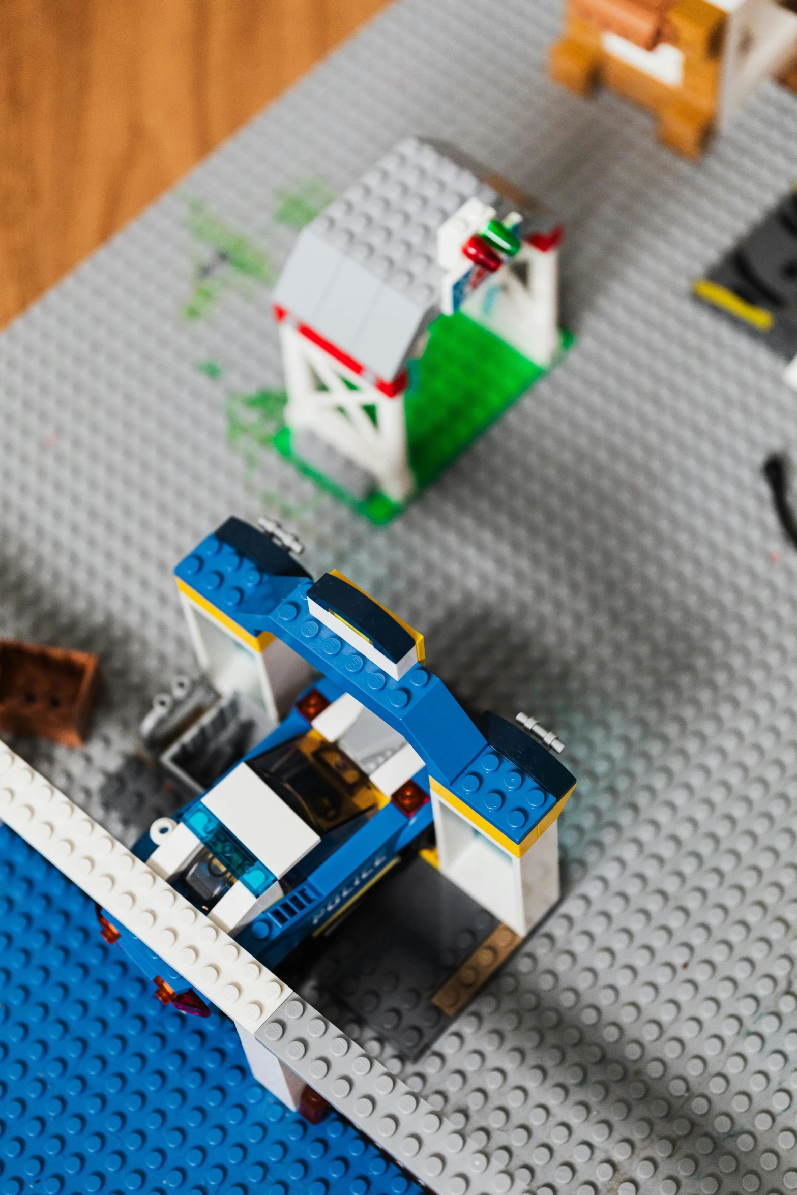 a table topped with legos sitting on top of a wooden floor, inspired by Rube Goldberg, unsplash, open bank vault, high angle close up shot, square, wide shot of a spaceship battle