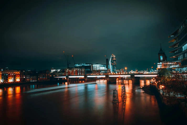 the london skyline is lit up at night, an album cover, pexels contest winner, 1 glowing bridge crossing river, lightroom preset, ominous photo, gloom and lights