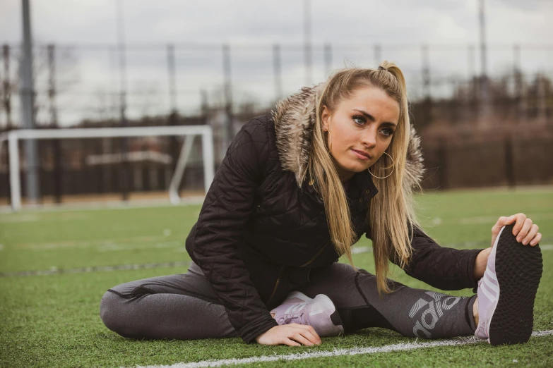 a beautiful young woman sitting on top of a soccer field, a portrait, inspired by Elsa Bleda, pexels contest winner, graffiti, wearing fitness gear, jessica nigri, sydney sweeney, stretch