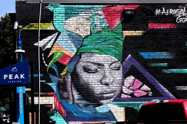 a mural painted on the side of a building, graffiti art, by artist, pexels, street art, african queen, painted on a brick wall, covered head, thumbnail