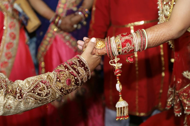 a close up of a person holding a person's hand, hurufiyya, wedding, red and blue garments, group photo, bracelets