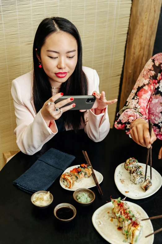 two women sitting at a table with plates of food, trending on unsplash, ukiyo-e, checking her cell phone, vp of marketing, sushi, dumplings on a plate