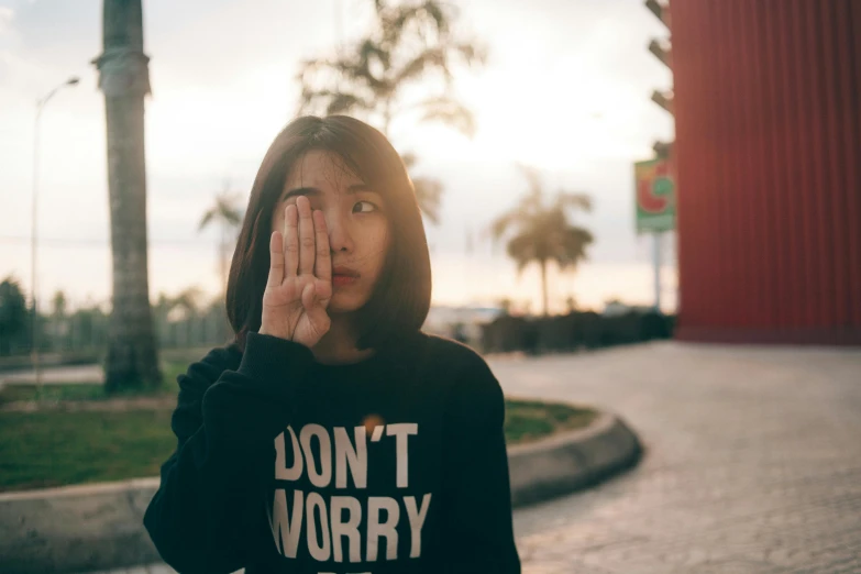a woman covering her face with her hands, pexels contest winner, wearing sweatshirt, young cute wan asian face, worry, lomography photo