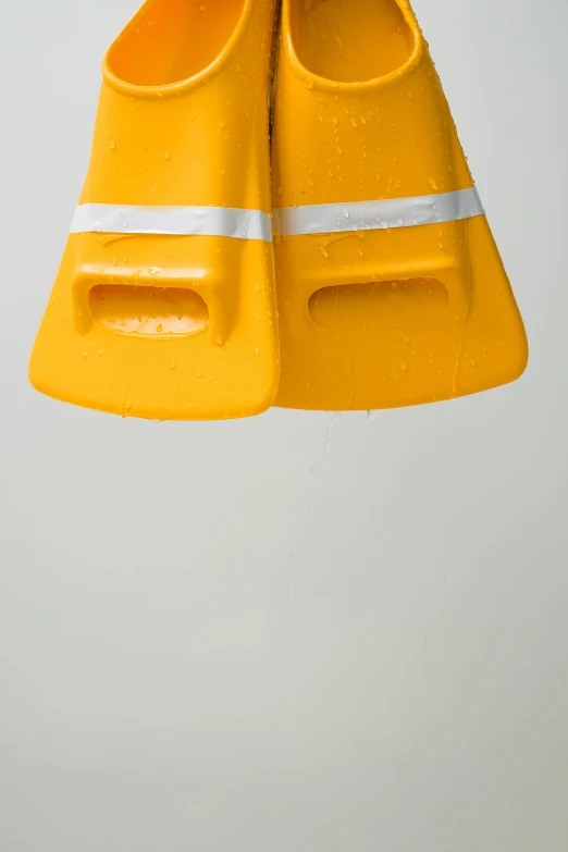 a pair of yellow diving fins hanging from a rope, by Doug Ohlson, unsplash, conceptual art, yellow hardhat, it\'s raining, portrait photo, an upside down urinal