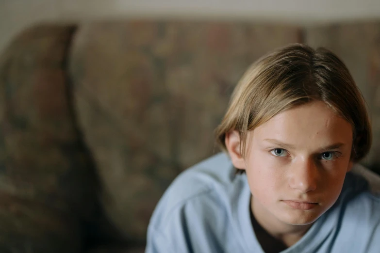 a young boy sitting on a couch with a remote in his hand, unsplash, hyperrealism, jamie campbell bower, medium head to shoulder shot, 15081959 21121991 01012000 4k, portrait of 14 years old boy