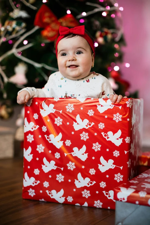 a baby sitting in a gift box in front of a christmas tree, a picture, by Julia Pishtar, shutterstock contest winner, happening, looking towards camera, graphic print, square, holy