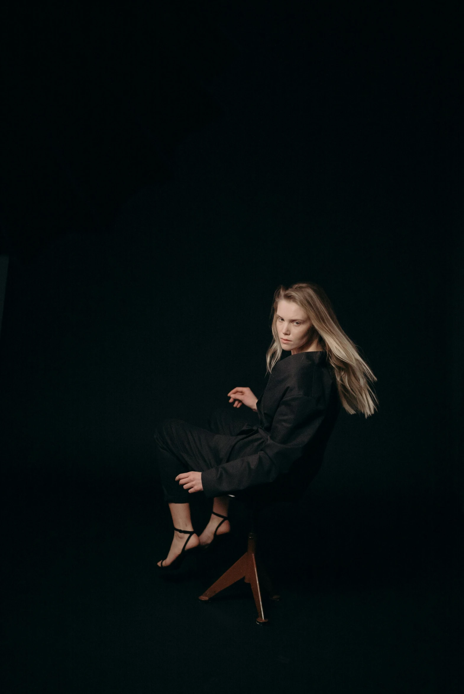 a woman sitting on a chair in the dark, an album cover, unsplash, realism, a full portrait of nordic female, pose 4 of 1 6, low quality photo, standing