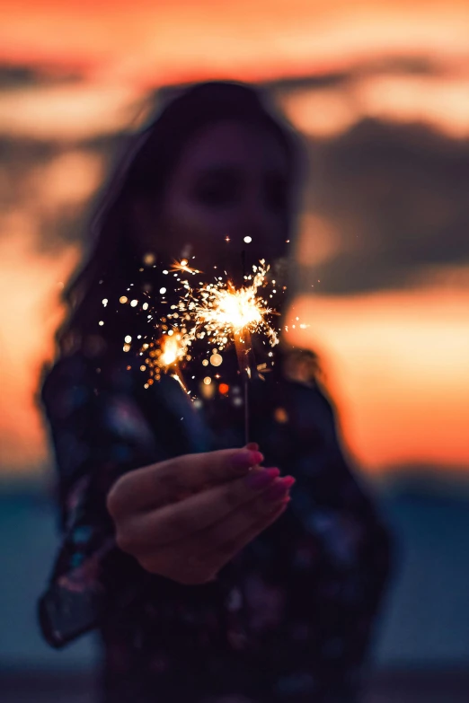 a woman holding a sparkler in her hand, pexels contest winner, light illumination at sunset, instagram post, paul barson, sequins