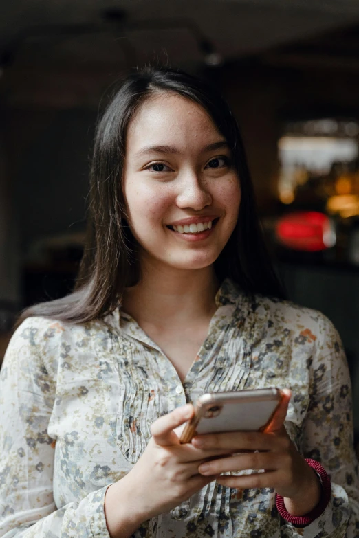 a woman smiles while looking at her cell phone, by Reuben Tam, pexels contest winner, happening, lovingly looking at camera, avatar image, asian female, wearing casual clothing