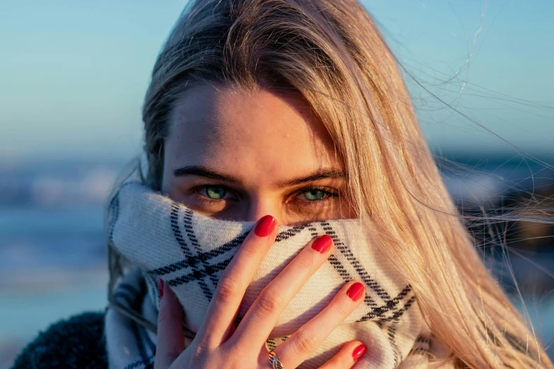 a woman covering her face with a scarf, inspired by Elsa Bleda, trending on pexels, aestheticism, blond hair blue eyes, painted nails, bags under eyes, ocean eyes