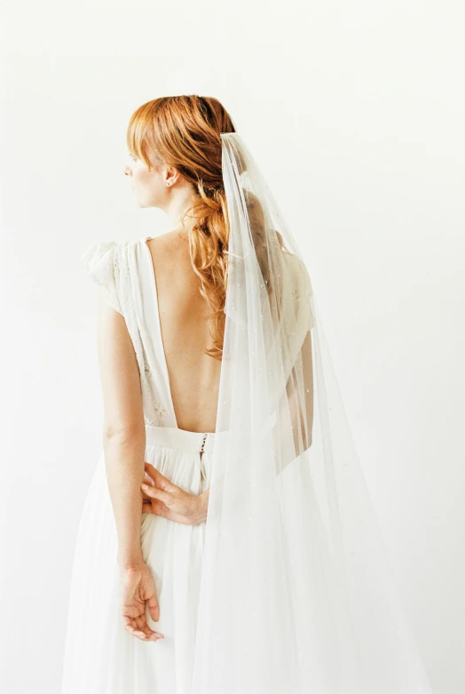 a woman in a wedding dress with a veil, in front of white back drop, back view », carson ellis, long red hair