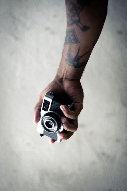 a person holding a camera in their hand, a tattoo, inspired by Gordon Parks, pexels contest winner, medium format, !!! colored photography, photography hight quality, a high angle shot