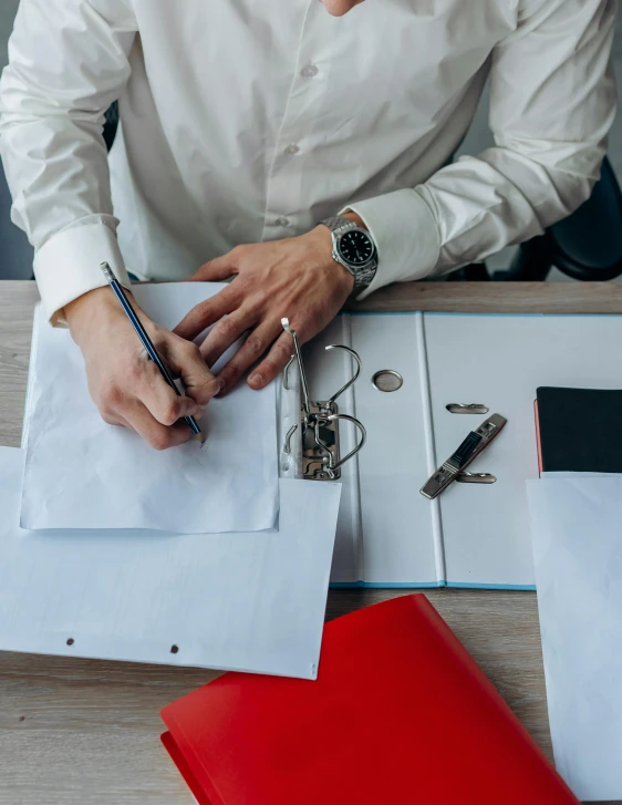 a woman sitting at a desk writing on a piece of paper, a screenshot, pexels contest winner, a handsome, holding a briefcase, wearing white shirt, redundancy